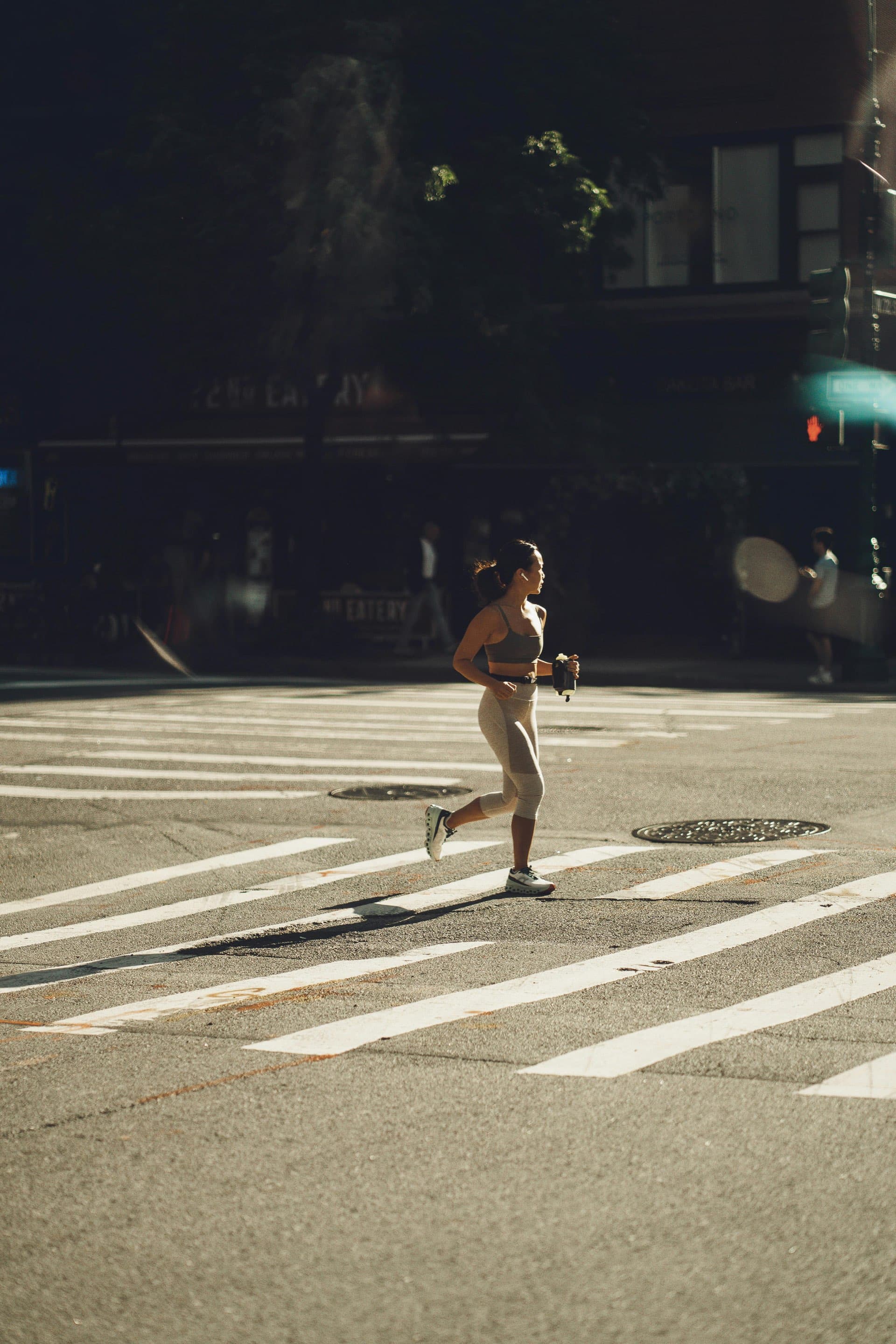 Runner crossing a city street in early morning light